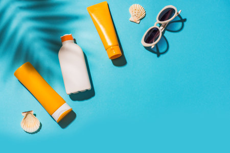 Sunblock lotion bottles and sunglasses on blue background,copy space. Summer vacation and skin care concept, sunscreen, spf uv-protect cosmetics.の写真素材