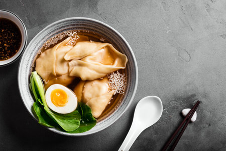 Homemade Chinese Wonton Soup with Bok Choy on concrete background, copy space. Miso soup with shrimp or pork wonton dumplings, edd and pok choi.の写真素材