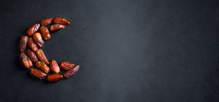 Ramadan Kareem with dates fruits arranged in shape of crescent moon on black background, top view, copy space. Muslim traditional Iftar food concept.の写真素材