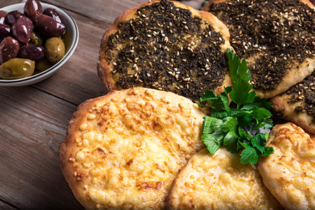 Manakeesh, arabic pizza, flat bread topped with zaatar spices and cheese. Homemade mediterranean flat bread manakish on wooden table close up.の写真素材