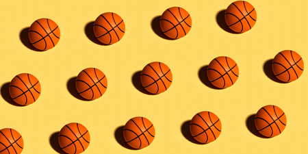 Trendy pattern made with orange ball for basketball on bright yellow background. Minimal trendy sport concept.の写真素材