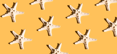 Summer pattern made with white starfish on bright yellow background. Minimal trendy summer concept.の写真素材