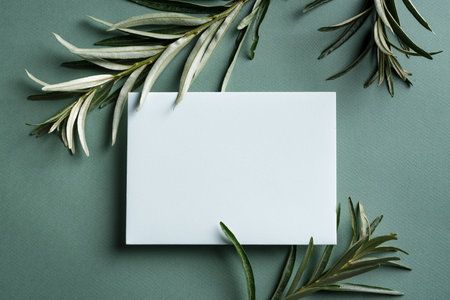 Greeting or invitation blank card and green eucalyptus plant leaves on dark green background. Stylish creative mock up, top view, copy spaceの写真素材