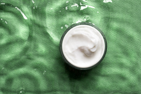 Jar of cosmetic cream on clear green water background, top view, copy space. Moisturizing organic beauty cream. Hydrating natural skin care and spa concept.の写真素材