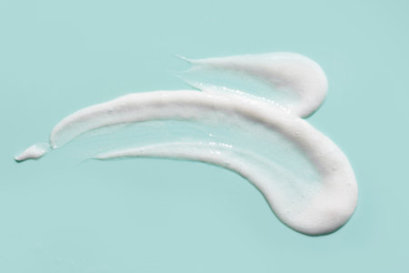 Cosmetic face cleansing mousse gel smudge drops texture on blue background. Smear sample of liquid...