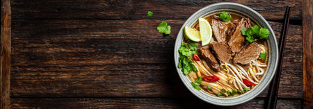 Pho Bo Vietnamese soup, bowl of fresh Asian soup with rice noodle, beef meat, herbs, soy sprouts and chili on wooden background, banner, copy space. Asian cuisine, comfort food template.の写真素材