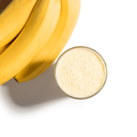 Banana smoothie and bananas isolated on white background, top view, copy space. Glass of banana blended protein drink, milkshake, design element.の写真素材