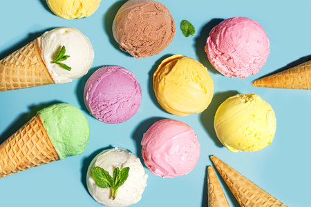 Assorted ice cream scoops with various flavors on blue background, top view. Ice creams or gelato with waffle cones, healthy summer dessert creative concept.の写真素材