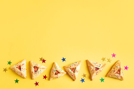 Purim cookies Hamantaschen in row with confetti and sugar sprinkles on yellow background, copy space. Purim banner.の写真素材