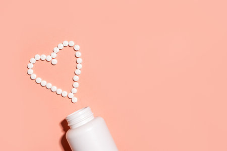 Heart shape made of white pills, minimal concept of cardio health on pink pastel background, top view, copy space. Supplements for female health care template. Pharmacy and cardiology banner designの写真素材