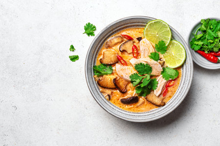 Tom Kha Gai Soup on white concrete background, top view, copy space. Bowl of traditional thai asian spicy coconut milk soup with chicken and shiitake mushrooms - tom kha kai soup.の写真素材