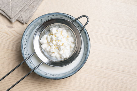 Milk kefir grains on stainer, top view, copy space. Preparing healthy fermented probiotic milk kefir...