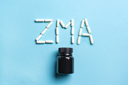 ZMA supplement capsules and plastic container on blue background, top view. Sport supplement for night recovery.の写真素材