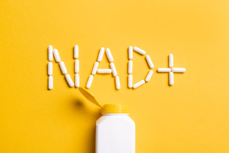 NAD+ supplement pills and plastic containers for anti-aging and biohacking on yellow background, top view. Letters NAD plus capsules.の写真素材