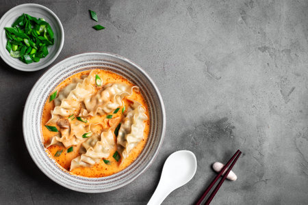 Thai Coconut Curry Dumpling Soup on concrete background, top view, copy space. Red curry wonton...