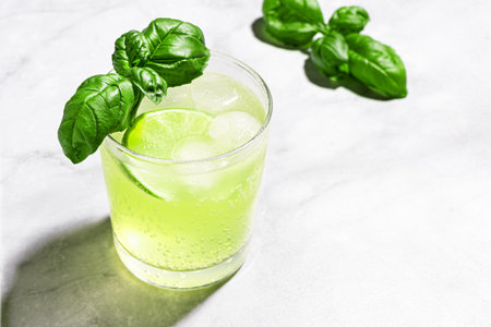 Lime Basil Mocktail with ice on white marble background, copy space. Green summer cocktail drink, refreshing tonic, citrus detox water. Basil smash.の写真素材