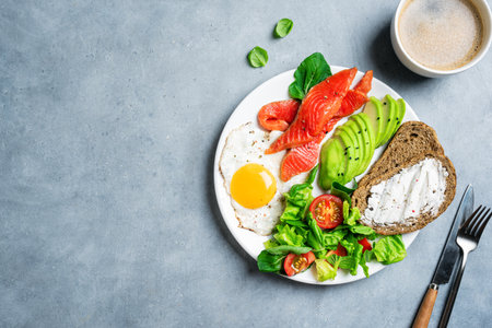 Balanced healthy breakfast plate - fried egg, toast, salmon, avocado and green salad. Balanced meal of protein, fat, complex carbohydrates and fiber Top view, copy space.の写真素材