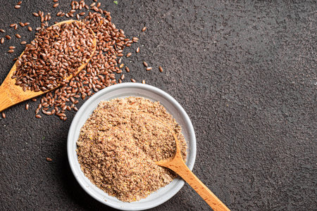 Flaxseeds on wooden spoon and ground of flax seeds, top view, copy space. Healthy eating. Organic product.の写真素材