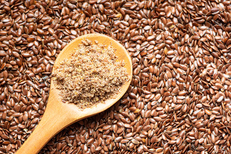 Flaxseeds as background and ground of flax seeds on wooden spoon, top view, copy space. Healthy food ingredient, superfood. Organic product.の写真素材