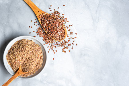 Flaxseeds whole and ground of flax seeds on marble background, top view. Healthy food ingredient, superfood. Organic product.の写真素材