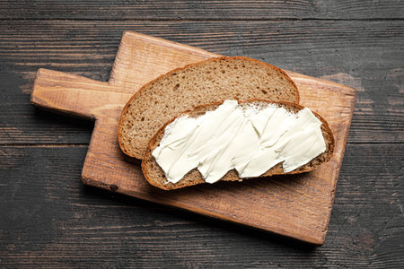Butter and bread for breakfast on wooden background, top view. Slices of sourdough with organic...