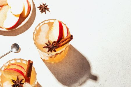 Autumn apple cocktail or mocktail drink. Apple cider with cinnamon and anise on white background, copy space.の写真素材