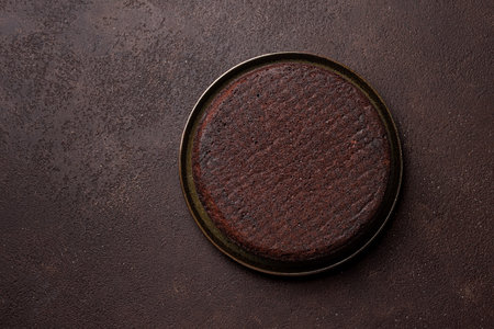 Chocolate sponge cake on dark brown background, top view, copy space. Round chocolate cake.の写真素材