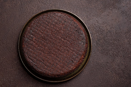 Chocolate sponge cake on dark brown background, top view, copy space. Round chocolate cake.の写真素材