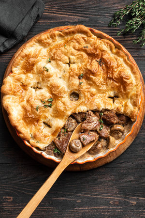Chicken and Mushroom Pie with crispy puff pastry crust on wooden background, top view. Seasonal hearty comfort meal - homemade creamy meat pie.の写真素材