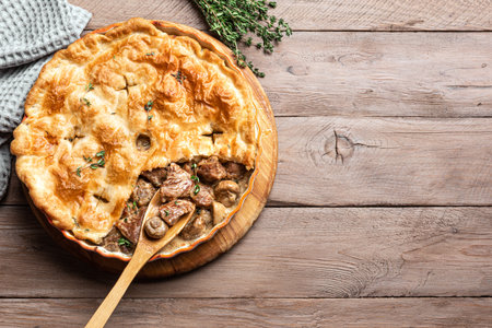 Chicken and Mushroom Pie with crispy puff pastry crust on wooden background, top view, copy space. Seasonal hearty comfort meal - homemade creamy meat pie.の写真素材