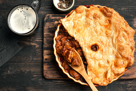 Beef steak pie with dark gravy and crispy puff pastry, top view. Homemade meat pie recipe, winter seasonal comfort food.の写真素材