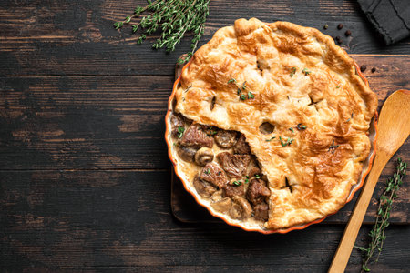 Beef Meat and Mushroom Pie on wooden background, top view, copy space. Seasonal hearty comfort meal - homemade creamy meat pie.の写真素材