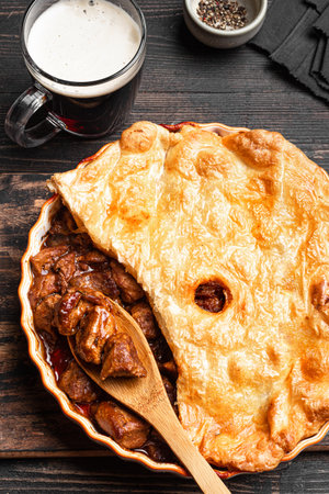 Beef steak pie with dark beer gravy and crispy puff pastry, top view. Homemade meat pie recipe, winter seasonal comfort food.の写真素材