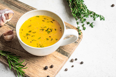 Beef bone broth with herbs (instant bouillon) in mug on white background with herbs and spices. Healthy food, drinkable collagen broth.の写真素材