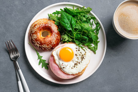 Bagel sandwiches with fried egg, cream cheese, ham and greens on concrete background, top view. Healthy balanced breakfast and coffee. Gluten free keto breakfast.の写真素材