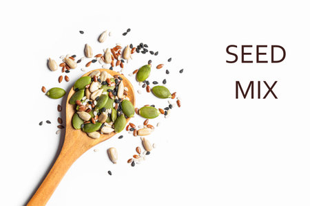 Mix of seeds on wooden spoon isolated on white background, top view, design element. Healthy eating ingredients texture. Pumpkin seeds, black and white sesame, sunflower seeds and linseeds mix for baking or salad topping.