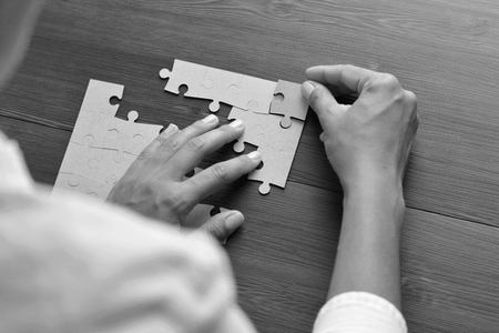 Close-up Of Businessman Hands Completing Jigsaw Puzzleの写真素材
