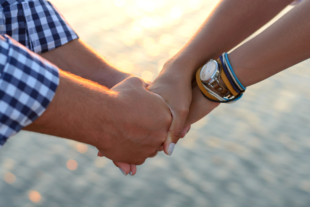 Two lovers (guy and girl) hold hands tightly on the beach.の写真素材