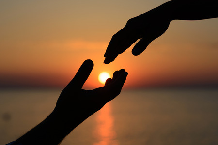 A man holds the sun in his hands and gives it to his beloved girl. Love and romance.の写真素材