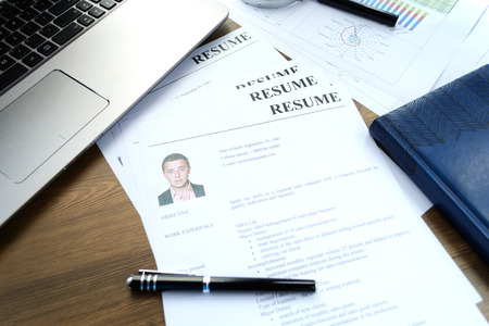 Resume (curriculum vitae, cv) and pen on a written wooden table.の写真素材