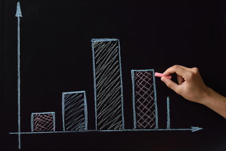 Business woman drawing colored chalk on a blackboard charts, plans, diagramsの写真素材