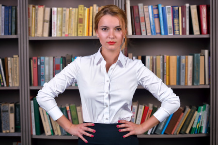 Business woman (student, manager, teacher) in the library near bookcaseの写真素材