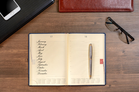 Title name of month and business accessories on desktop: notebook, diary, fountain pen, cufflinks, glasses. Macro with blur and soft focusの写真素材