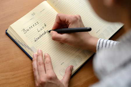 emale hand with french manicure writing in a business diary fountain pen. Macro with blur and soft focus.の写真素材