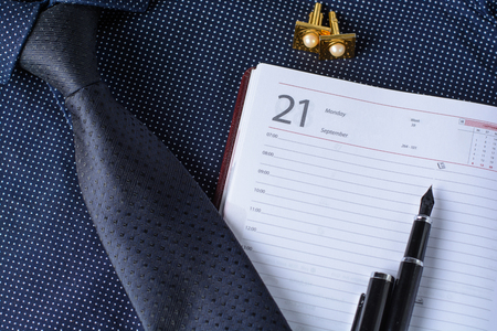 Business accessories (cufflinks, fountain pen, tablet, phone, notepad, dairy) in the men's classic shirt with tieの写真素材