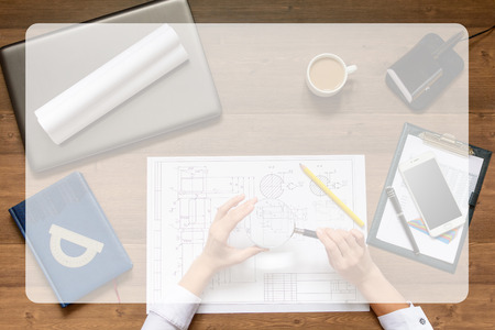 Girl is sitting at table with business accessories, notebook (diary), cup of coffee and a laptop and works with drawings, graphs, tables. Top view.の写真素材