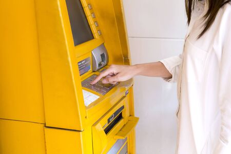 Close up female hand pushing passwords bank on the pin button of ATM machine to withdraw moneyの写真素材