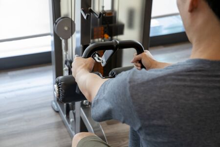 Young man beginner exercising with dumbbell flexing muscles at gym, sport training concept