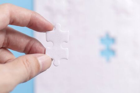 hand holding one part out of group with jigsaw puzzle on blue background, Working concepts separated...