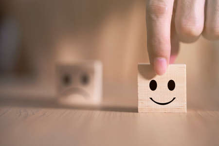 Businessman chooses a smile emoticon icons face happy symbol on wooden block , Services and Customer satisfaction survey conceptの写真素材